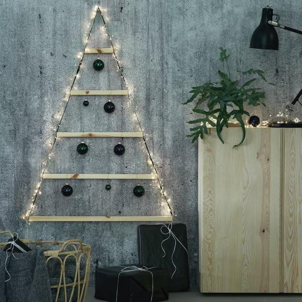 Árbol de Navidad de pared hecho con listones de madera y guirnalda de luces.