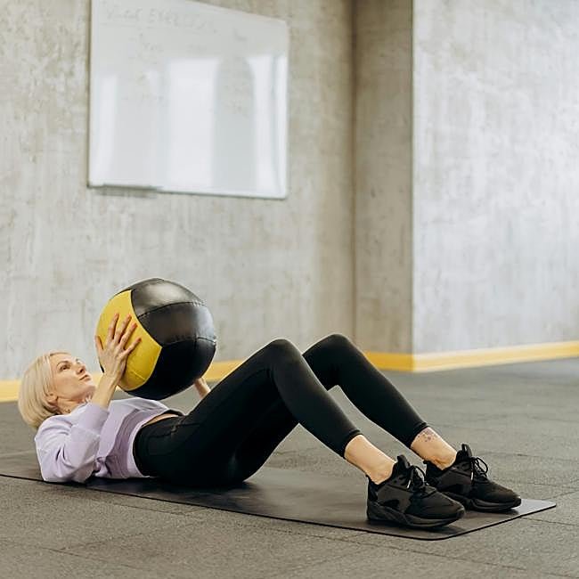 Mujer practicando Pilates con pelota.