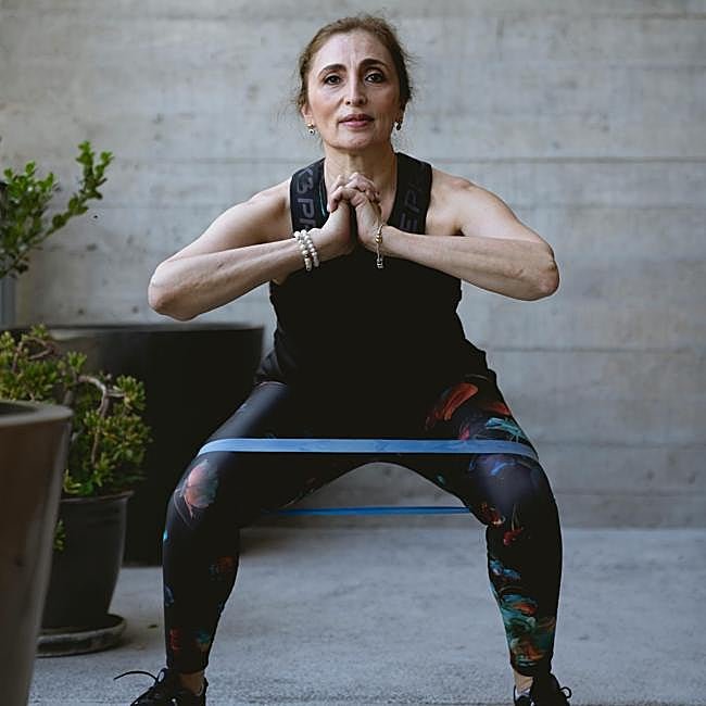 Mujer haciendo sentadillas con una banda de resistencia.