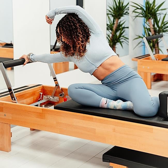 Mujer haciendo Pilates en maquina.