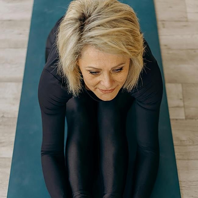Mujer practicando yoga sobre esterilla.