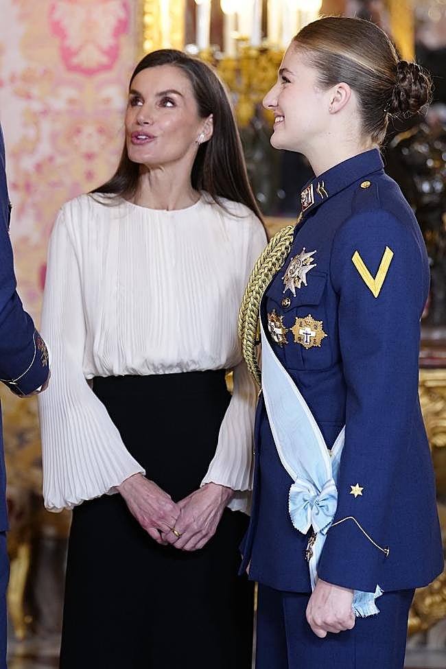La reina Letizia estrena una blusa blanca plisada de mangas acampanadas.