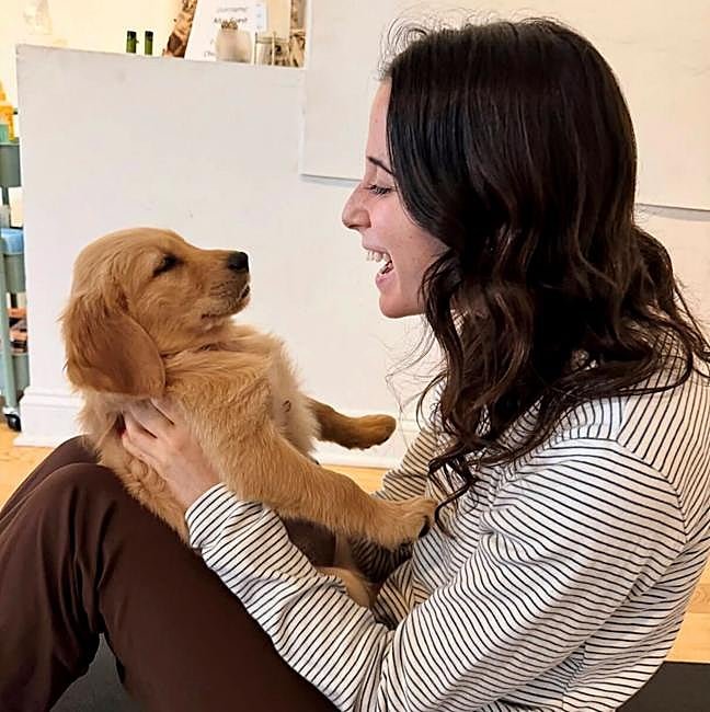 Mujer practicando yoga con el método viral puppy therapy.