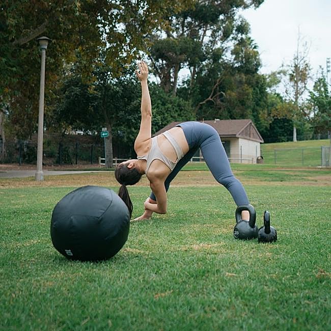 Mujer haciendo ejercicios con pelota y mancuernas.