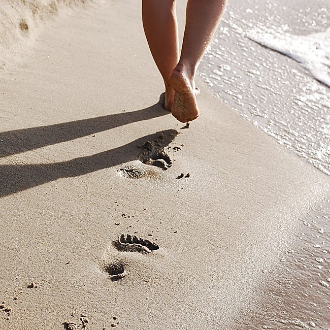 Mujer caminando por la orilla de la playa.