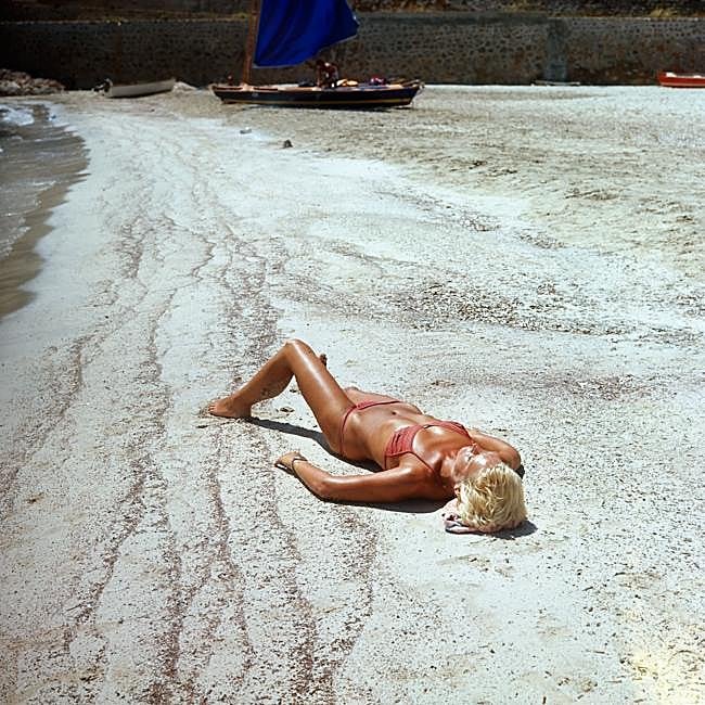 Una mujer se broncea tumbada al sol en la orilla de la playa.