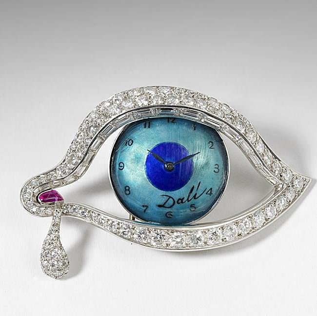 El broche El ojo del tiempo, elaborado con platino, rubí natural, diamantes, esmalte y y un relok con mecanismo Movado 50SP.